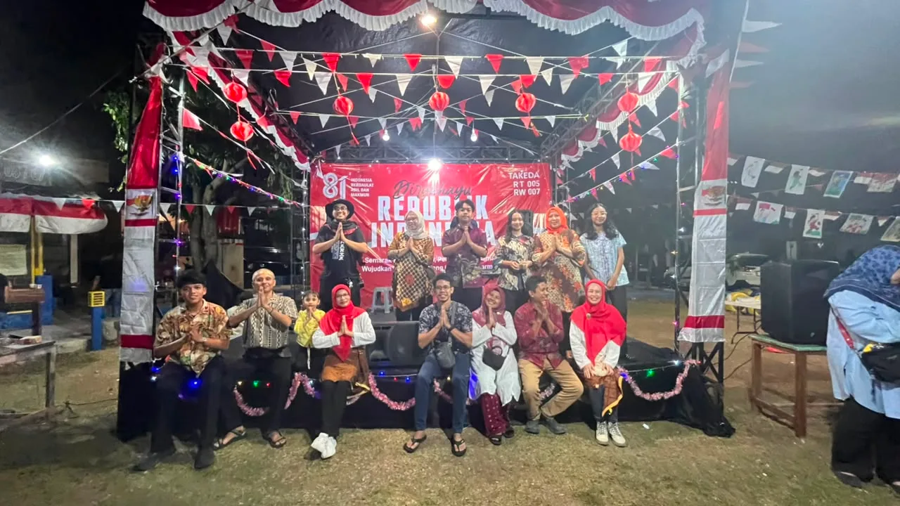Warga berfoto bersama di panggung Takeda dengan hiasan dan bendera merah putih.